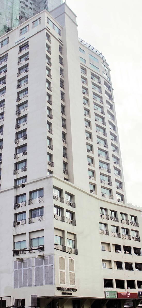 An old greyscale photograph of a white building showing the Torre Lorenzo residences' facade.